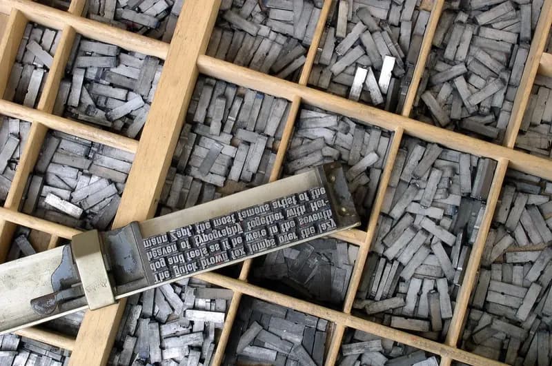 Trays of metal printing type, with a composing stick holding a line of set text across them.
